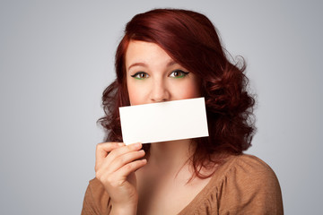 Cute girl holding white card at front of her lips with copy spac