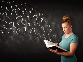 Pretty woman reading a book with question marks coming out from