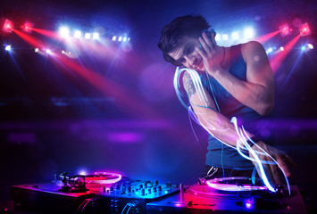 Obraz na płótnie Canvas Disc jockey playing music with light beam effects on stage