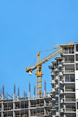 Crane and building construction site against blue sky