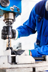 Handwerker bohrt mit Bohrmaschine in Fabrik