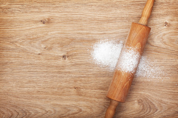 Rolling pin with flour on wooden table