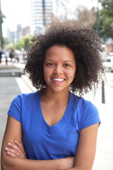 Young woman with curly hair and crossed arms in the city