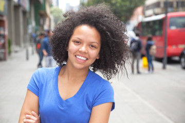 Fototapeta na wymiar Laughing young woman with curly hair in the city