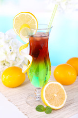 Glass of cocktail on table on light blue background