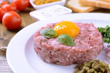 Delicious steak tartare with yolk on plate on table close-up