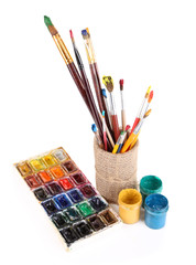 Composition with brushes in vase and paints isolated on white