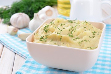 Delicious mashed potatoes with greens in bowl on table close-up