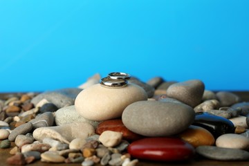 Fototapeta na wymiar Wedding rings on rocks on blue background