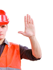 Man worker in safety vest and hard hat showing stop hand