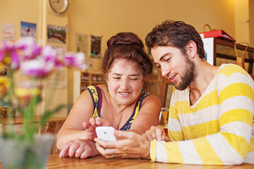 Grandson teaching his grandmother how to use mobile phone