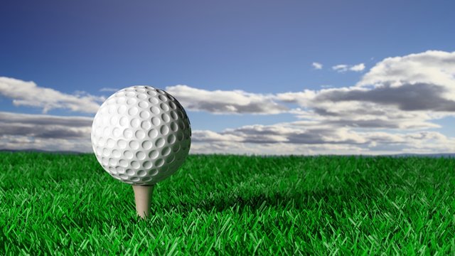 Golf ball on tee on grass with blue sky