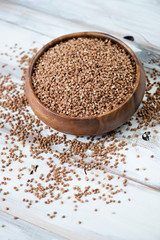 Wooden bowl with raw buckwheat, vertical shot