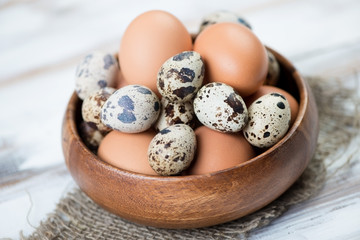 Wooden bowl with raw chicken and quail eggs, close-up