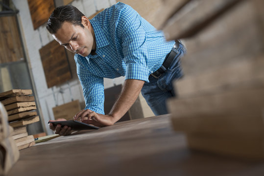 A Young Man In A Workshop Using A Digital Tablet In His Work. 
