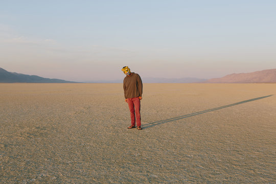 The Landscape Of The Black Rock Desert In Nevada. A Man Wearing An Animal Mask. Casting A Long Shadow On The Ground. 