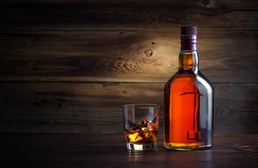 Photo sur Plexiglas Alcool bouteille et verre de whisky avec de la glace sur un fond en bois