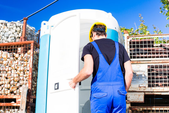 Bauarbeiter benutzt mobile Toilette einer Baustelle