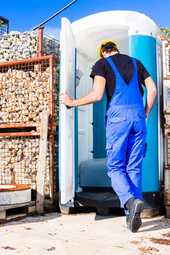 Bauarbeiter benutzt mobile Toilette einer Baustelle