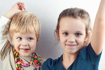 Small blond boy and girl pull hands up
