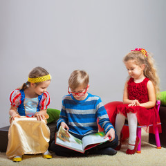 Preteen boy reading a fairy tale to two little girls