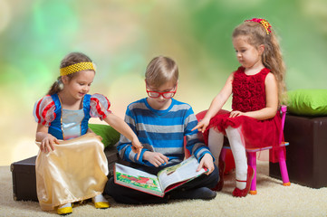 Preteen boy reading a fairy tale to two little girls