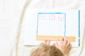 Child designing and measuring a house
