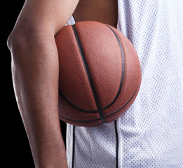 Image of a basketball player holding a ball against dark backgro