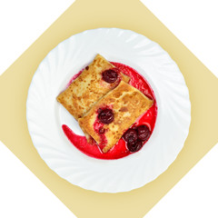 Dish of crepes with cherry sause on white plate.