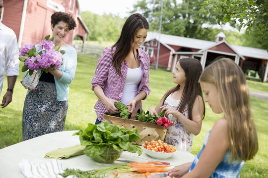 Family Party. Five People, Parents And Children Around A Table Preparing A Meal Of Fresh Picked Salads, Fruits And Vegetables Together. 
