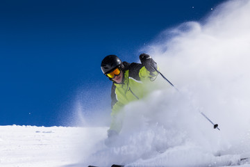 Alpine skier on piste, skiing downhill