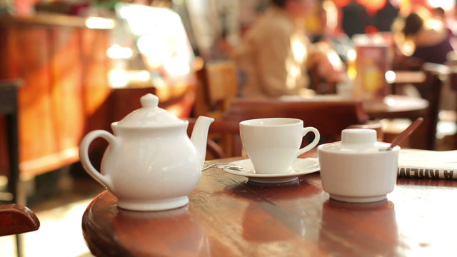 Teapot and sugar-bowl on the table in crowded cafe
