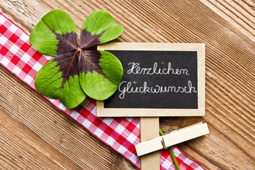 Holzhintergrund mit Tafel und Kleeblatt, Herzlichen Glückwunsch