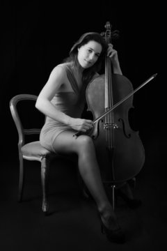 Beautiful brunette playing cello with selective light in red dre