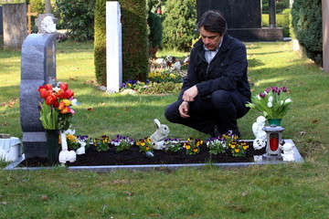Mann trauert am Grab seiner Frau, Friedhof