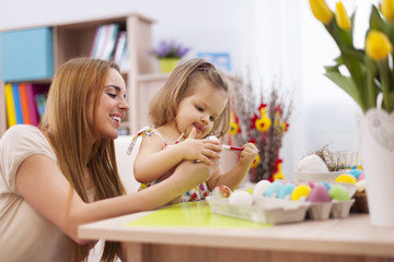 Obraz na płótnie Canvas Focus little girl painting easter eggs with mother