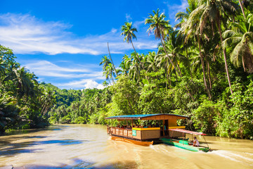 Exotic cruise boat with tourists on a jungle river Loboc, Bohol