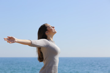 Happy woman breathing deep fresh air and raising arms