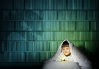 boy under the covers with a flashlight