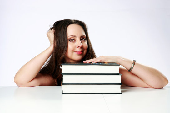 Happy woman sitting on the table with books over gray background
