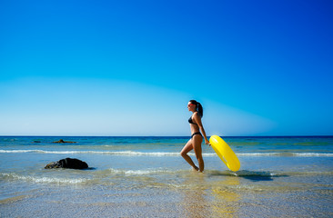 Beach Girl Walking with Yellow Float in Cadiz Beach.