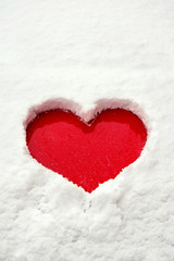 Love red heart shape in snow on red car. Close-up.