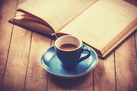 blue cup of the coffee and vintage book.