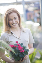 handsome woman holding one potted flowers in a garden center