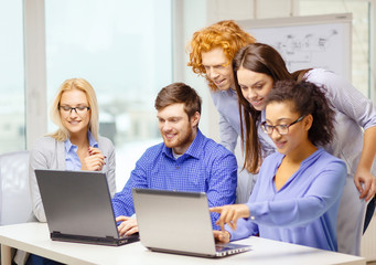 smiling team with laptop computers in office