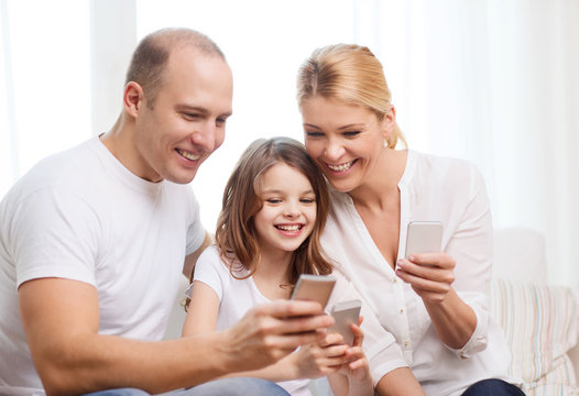 parents and little girl with smartphones at home