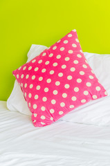 Colorful polka pillow on white bed