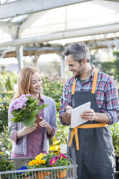 gardener using his digital tablet to advise a female client who