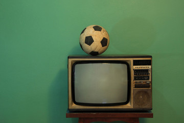 An old soccer ball on a retro TV with retro green paint wall