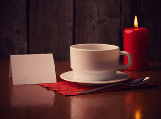 cup of coffee, candle and paper on wooden background